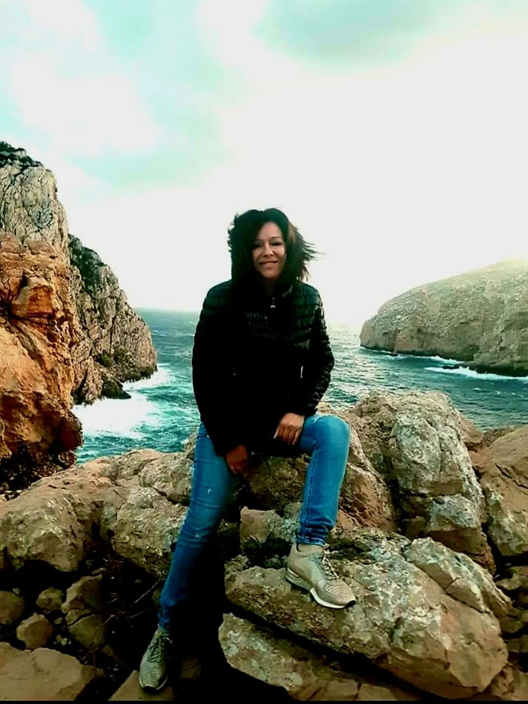 una persona seduta su una roccia vicino all'acqua